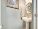 Charming half-bath featuring a pedestal sink, decorative mirror, and framed artwork on a light green wall at 1778 Sundance Chase Rd, Minneola, FL 34715