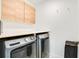 Laundry room with modern, front-loading washer and dryer, wood cabinets, and white walls at 1778 Sundance Chase Rd, Minneola, FL 34715