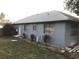 Back exterior view of the single-story home with access door and multiple windows with blinds at 1886 Elkcam Blvd, Deltona, FL 32725