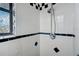 White tiled shower in bathroom with a decorative window and black accents at 1886 Elkcam Blvd, Deltona, FL 32725