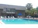 Inviting community pool with lounge chairs and umbrellas near building with wavy window decor at 1928 Conway Rd # 27, Orlando, FL 32812