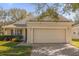 Beige home featuring a two-car garage and a brick paver driveway, with manicured landscaping and inviting curb appeal at 2513 Castle Pines St, Clermont, FL 34711