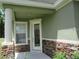 House exterior featuring a light green facade, stone accents, and a white front door at 3260 Sorrel Ct, Deltona, FL 32725