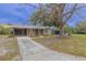 View of the home's exterior, featuring a screened-in porch, neutral color, and mature trees at 124 Pinecrest Dr, Sanford, FL 32773