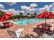 Relax and unwind at the community pool with ample seating, red umbrellas, and lush landscaping at 16737 Meadows St, Clermont, FL 34714
