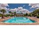 Beautiful community pool surrounded by palm trees, lounge chairs, and a covered pavilion for relaxing by the water at 16737 Meadows St, Clermont, FL 34714