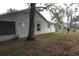 Exterior of home shows light gray siding and large tree in yard filled with fallen leaves at 32512 Oak Park Dr, Leesburg, FL 34748