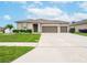 Tan house with double garage and manicured lawn at 5681 Western Sun Dr, St Cloud, FL 34771