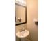 A clean half bathroom featuring a pedestal sink, framed mirror, and neutral wall color at 8189 Roseville Rd, Davenport, FL 33896