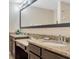 Double vanity bathroom featuring granite countertops, dark cabinets, and a large mirror at 8189 Roseville Rd, Davenport, FL 33896