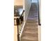 Carpeted staircase with decorative black iron banister and neutral walls leading to the upper level at 8189 Roseville Rd, Davenport, FL 33896