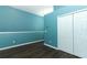 Bedroom featuring vibrant blue walls, dark wood floors, and a spacious closet, blending style and functionality at 1044 Pavia Dr, Apopka, FL 32703