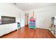 Bright bedroom showcasing wood floors, white walls, a rainbow-colored storage unit, and natural light at 24908 County Road 561, Astatula, FL 34705