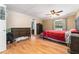 Bright main bedroom with wood flooring, a ceiling fan, and a dark wood bed frame with red comforter at 24908 County Road 561, Astatula, FL 34705