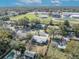 An aerial view of the neighborhood showing nearby school, swimming pool, and tree-lined streets under a sunny, partly cloudy sky at 3309 Drake Dr, Orlando, FL 32810