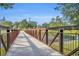 An exterior view of a pedestrian bridge with metal railings over a waterway in a public park under a blue sky at 3309 Drake Dr, Orlando, FL 32810
