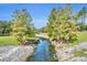 An exterior view of a gently flowing creek in a public park with rock lined banks and mature trees and vegetation at 3309 Drake Dr, Orlando, FL 32810