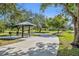 An exterior view of a public park with a covered picnic table, concrete walkway, and mature trees on a sunny day at 3309 Drake Dr, Orlando, FL 32810