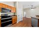 Kitchen features stainless steel appliances, wood cabinets, wood flooring, and a ceiling fan in adjacent room at 3608 Mount Hope Loop, Leesburg, FL 34748