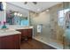 Modern bathroom featuring double sinks, wood cabinets, a large mirror, and a frosted glass walk-in shower at 442 Treviso Dr, Poinciana, FL 34759