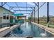 Large screened-in pool with a water feature and an in-pool seating area and umbrella at 442 Treviso Dr, Poinciana, FL 34759