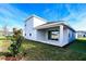 A covered patio sits off the back of this home in a grassy yard with a freshly planted tree at 4425 Lions Gate Ave, Clermont, FL 34711