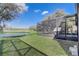 View of a manicured lawn extending to a screened-in patio and a picturesque pond at 9716 Pecky Cypress Way, Orlando, FL 32836