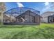 Rear exterior view of a home with a large screened-in patio overlooking a lush lawn at 9716 Pecky Cypress Way, Orlando, FL 32836