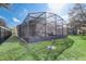 Exterior view of a house and screened-in patio with manicured lawn and fenced perimeter at 9716 Pecky Cypress Way, Orlando, FL 32836
