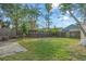 A grassy backyard enclosed by a wood fence with mature trees providing shade at 9836 Dean Cove Ln, Orlando, FL 32825