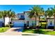 Charming two-story home with a two-car garage, stone accents, lush lawn, and tropical palm trees at 10680 Royal Cypress Way, Orlando, FL 32836