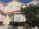 Two-story townhome with light-pink and beige exterior, and a well-manicured front yard at 1128 S Beach Cir, Kissimmee, FL 34746