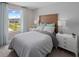 This modern bedroom features a wood headboard, white nightstands, a comfortable bed, and a window with blue curtains at 1309 Coral Bean Ln, Winter Springs, FL 32708
