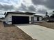 Modern home exterior features a dark-colored garage door and a concrete driveway at 150 Marion Oakes Trl, Ocala, FL 34473