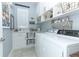 Well-lit laundry room with white cabinets, folding counter, shelving, tile floors and modern washer and dryer at 179 Hillcrest Dr, Oviedo, FL 32765