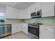 Modern kitchen with white cabinets, stainless steel appliances and light green backsplash at 2031 Eaton St, Maitland, FL 32751