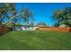 Large backyard with a grassy area, wooden fence, and mature trees at 2414 Herbison Dr, Orlando, FL 32810