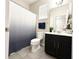 Well-lit bathroom with dark vanity, white counter, and a shower with a patterned blue shower curtain at 2931 Top Water Way, Kissimmee, FL 34746