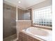 Bathroom with a tiled shower, and a bathtub under a block glass window at 4901 Marbella Isle Dr, Orlando, FL 32837