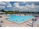 Community pool with plenty of lounge chairs and people swimming at 5999 Lake Pointe # 609, Orlando, FL 32822
