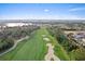 Scenic aerial view of the golf course featuring lush green fairways, sand traps, and a view of lake and houses nearby at 9573 Meadow Hunt Way, Winter Garden, FL 34787