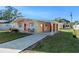 Tan mid-century home with orange door, landscaped lawn, and long driveway at 1514 Doreen Ave, Ocoee, FL 34761