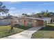 Tan mid-century modern home with orange door and a carport at 1514 Doreen Ave, Ocoee, FL 34761