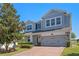 Charming two-story home featuring a gray exterior, brick driveway, and manicured landscaping at 15547 Hamlin Blossom Ave, Winter Garden, FL 34787