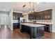 Kitchen boasts dark cabinets, stainless steel appliances, island, quartz counters, and stylish pendant lights at 15547 Hamlin Blossom Ave, Winter Garden, FL 34787