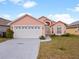 Two-story peach house with a two-car garage and well-maintained lawn at 1614 Stanbury Dr, Orlando, FL 32818
