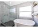 Modern bathroom featuring a shower and soaking tub, with stylish tile work and natural light from the window at 2551 Bear Creek Ct, Kissimmee, FL 34747