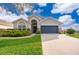 Charming single-story home featuring a blue garage door, arched entry, and lush landscaping at 2551 Bear Creek Ct, Kissimmee, FL 34747