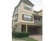 Tan three-story townhome with brown garage door, balcony, and landscaping at 2586 Grand Central Pkwy # 1, Orlando, FL 32839