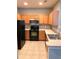 L-shaped kitchen with wood cabinets, stainless steel appliances, and tile flooring at 2586 Grand Central Pkwy # 1, Orlando, FL 32839